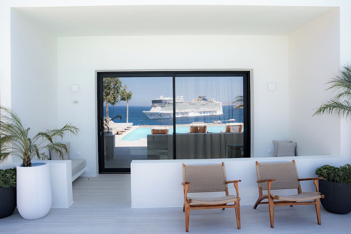 Un balcón con dos sillas de mimbre, una piscina y vistas a un crucero.