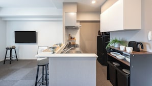 A compact kitchen with a central island, built-in appliances, and a flat-screen TV mounted on the wall.