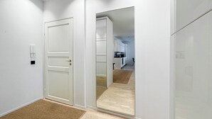 A hallway with a mirrored wall, a door with a keyhole, and a small rug on the floor.