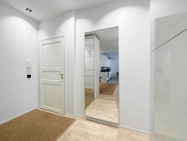A hallway with a mirrored wall, a door with a keyhole, and a small rug on the floor. - Stylish Downtown 2BR Flat with Sauna and Work Area (Helsinki)