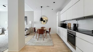 A modern kitchen with white cabinets, a black countertop, and a round dining table with chairs.