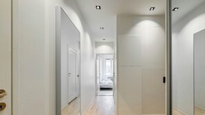 A hallway with wooden flooring, white walls, and doors leading to bedrooms.