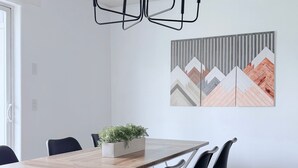 Ein moderner Essbereich mit einem Holztisch, schwarzen Stühlen und einer hängenden Leuchte.