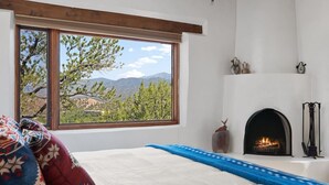 A bedroom with a large window, a fireplace, and a view of mountains.