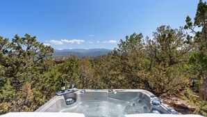 A hot tub with a clear view of mountains and trees in the background.