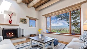 A cozy living room with a fireplace, comfortable seating, and a large window offering a scenic view.