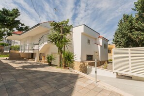 A modern two-story house with a covered patio, a staircase, and a fenced garden area.
