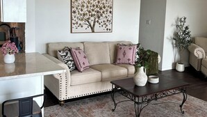 Un salon avec un canapé beige, une table basse et un tapis.