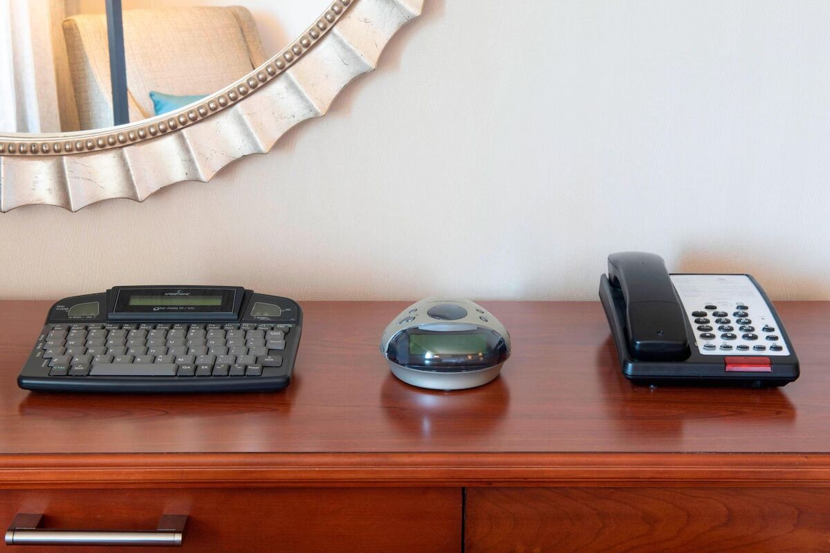 Un escritorio de madera con una computadora de escritorio, una cámara digital y un teléfono.