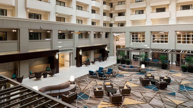A spacious hotel lobby with multiple seating areas, a central atrium, and a modern design.