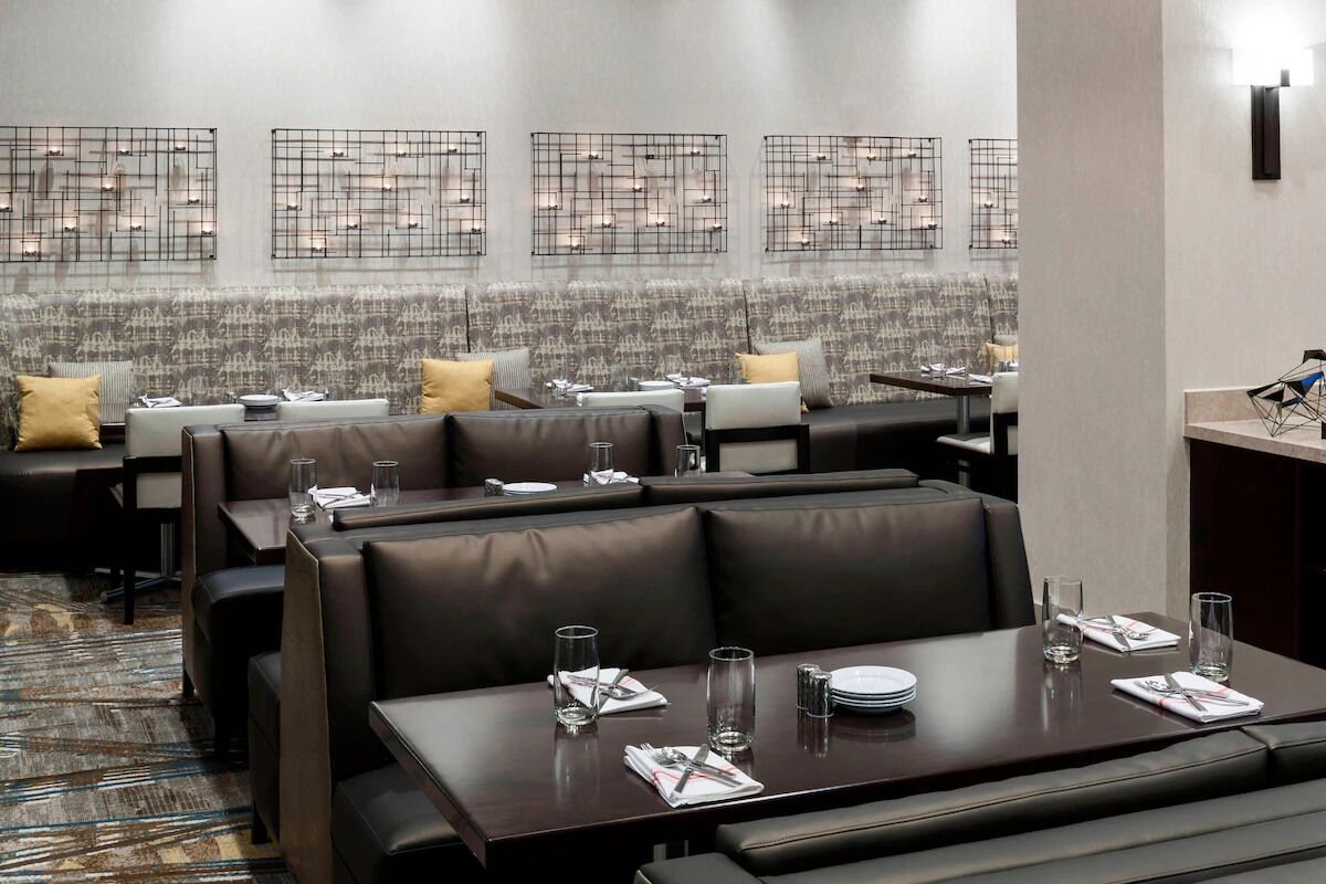 Un restaurant avec des banquettes et des tables, chaque ensemble comprenant un couvert et des verres.