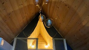 A wooden cabin with a triangular roof, a ladder leading to a loft area, and a small window with a mesh screen. - CollinéA Chalet "CanopéA" 28 m² Private SPA (Bathernay)
