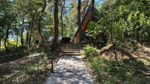 A wooden pathway leading to a building surrounded by trees. - CollinéA Chalet "CanopéA" 28 m² Private SPA (Bathernay)