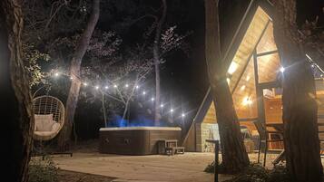 Un espace extérieur accueillant, doté d’un jacuzzi, d’une chaise suspendue et de guirlandes lumineuses.