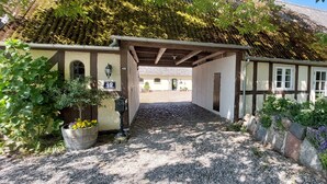 A traditional European-style building with a cobblestone entrance, a wooden gate, and a small garden area with potted plants and a seating area. - Rødkærgård Bed & Breakfast (Kerteminde)