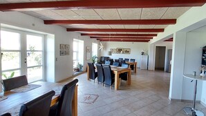 A dining area with a wooden table and chairs, a ceiling with exposed beams, and a bookshelf with books. - Rødkærgård Bed & Breakfast (Kerteminde)