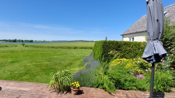 A well-maintained garden with a wooden deck, a lawn, and a variety of plants. - Rødkærgård Bed & Breakfast (Kerteminde)