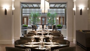 A modern dining area with tables set for a meal, large windows, and indoor plants. - 3 Units Quiet Retreat Perfect for Visiting Fair Oaks Mall | Free Parking (Fairfax)