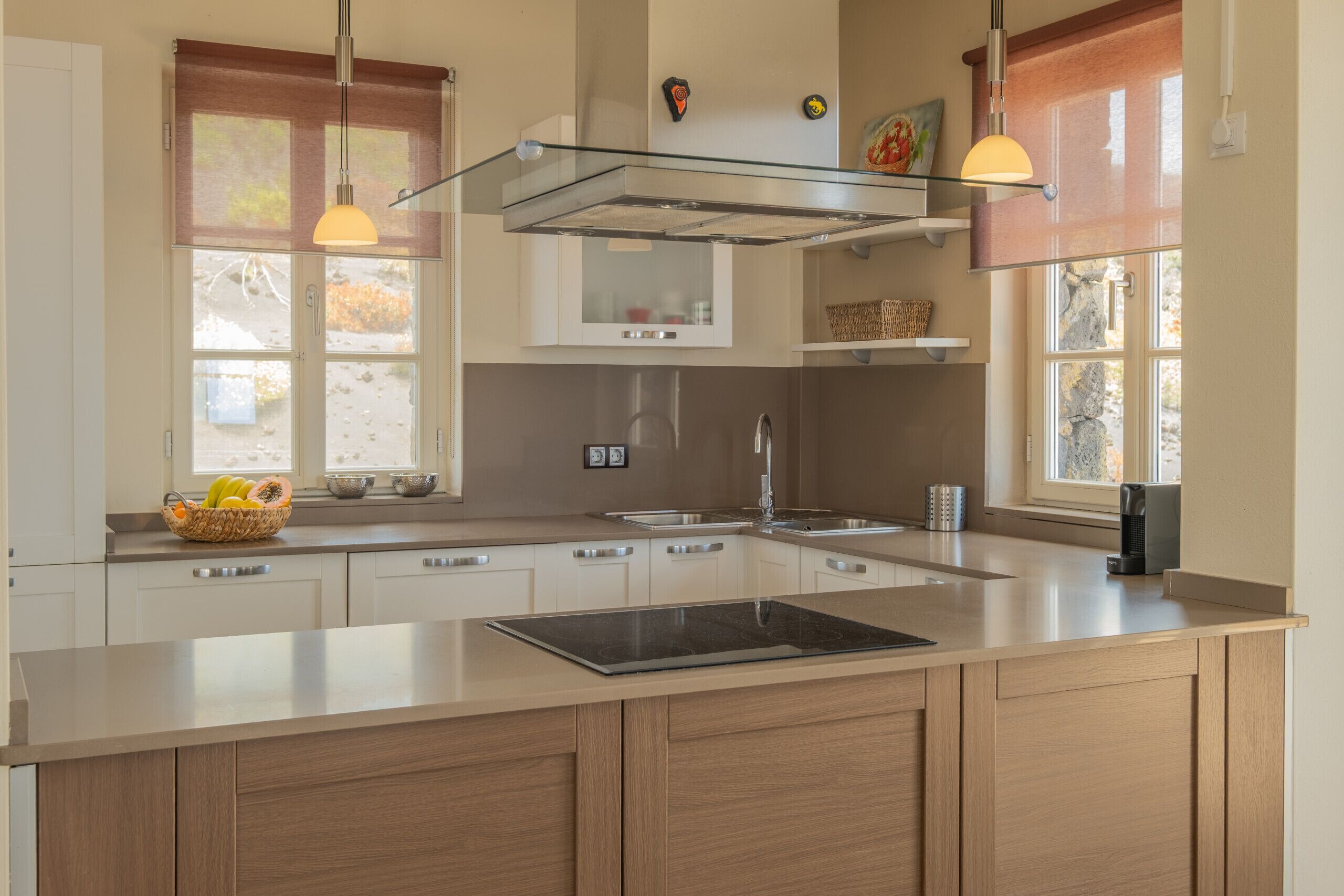 Een moderne keuken met een groot kookeiland, roestvrijstalen apparatuur en hanglampen.