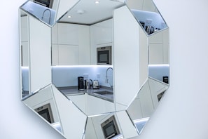 A hexagonal mirror reflecting a modern kitchen with a microwave, toaster, and coffee maker.