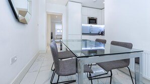 A modern kitchen with a glass dining table and chairs, a microwave, and a built-in oven.