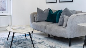 A modern living room with a grey sofa, a round coffee table, and a patterned rug.