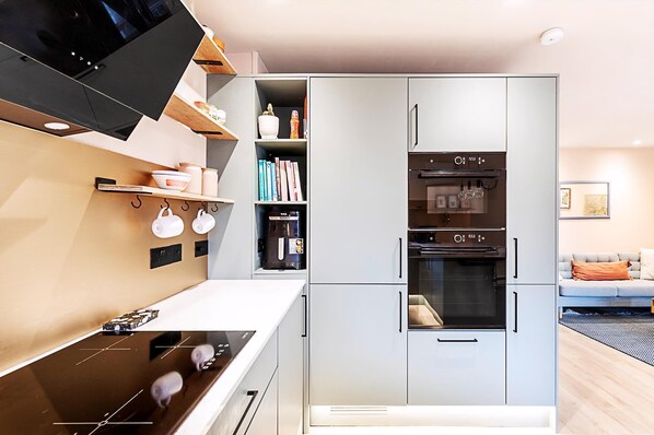A modern kitchen with a built-in oven, a microwave, and a coffee machine.