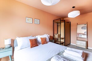 A bedroom with a bed, a nightstand, a wardrobe, and a mirror.