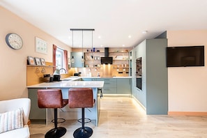 A modern kitchen with a central island, pendant lights, and a built-in oven.