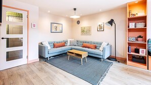 Una sala de estar moderna con un sofá azul claro, una mesa de centro, una lámpara de pie y una estantería.