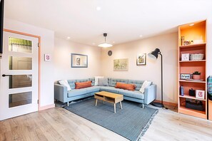 A modern living room with a light blue sofa, a coffee table, a floor lamp, and a bookshelf.