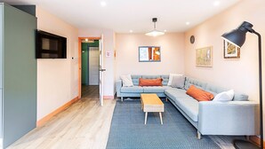 A modern living room with a sectional sofa, a coffee table, a flat-screen TV, and artwork on the walls. - Bright 2-bed Home Near Putney Riverside (London)
