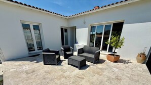 A patio with outdoor furniture, a potted plant, and a large window. - House Sainte-Marie de Ré (Sainte-Marie-de-Ré)