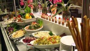 Un buffet proposant une variété de plats, notamment des salades, des sauces et du pain.
