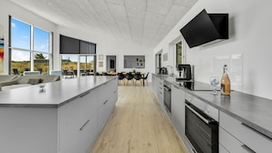 A modern kitchen with a large island, built-in appliances, and a flat-screen TV mounted on the wall. - Gorgeous home in Ringkøbing with sauna (Ringkøbing)