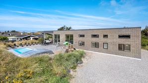 A modern building with a brick facade, a swimming pool, outdoor seating, and a playground. - Gorgeous home in Ringkøbing with sauna (Ringkøbing)
