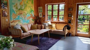A cozy room with a large map, wooden walls, a sofa, a table, and a window with a view.