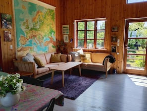 Une pièce chaleureuse avec une grande carte, des murs en bois, un canapé, une table et une fenêtre donnant sur un paysage agréable.