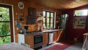 A wooden cabin kitchen with a stove, oven, sink, and refrigerator.