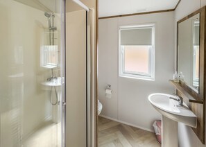Een moderne badkamer met een douchecabine van glas, een wastafel met houten meubel en een raam voor natuurlijk licht.