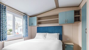Quarto com cama, janela com cortinas e armários embutidos.