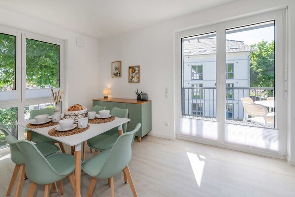 A dining area with a table set for four, a green cabinet, and a sliding glass door leading to an outdoor balcony.