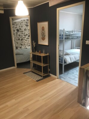 A room with a wooden floor, a bunk bed, a small wooden shelf with decorative items, a framed artwork on the wall, and a patterned rug. - Charming rentals in the heart of Auvergne (Yronde-et-Buron)