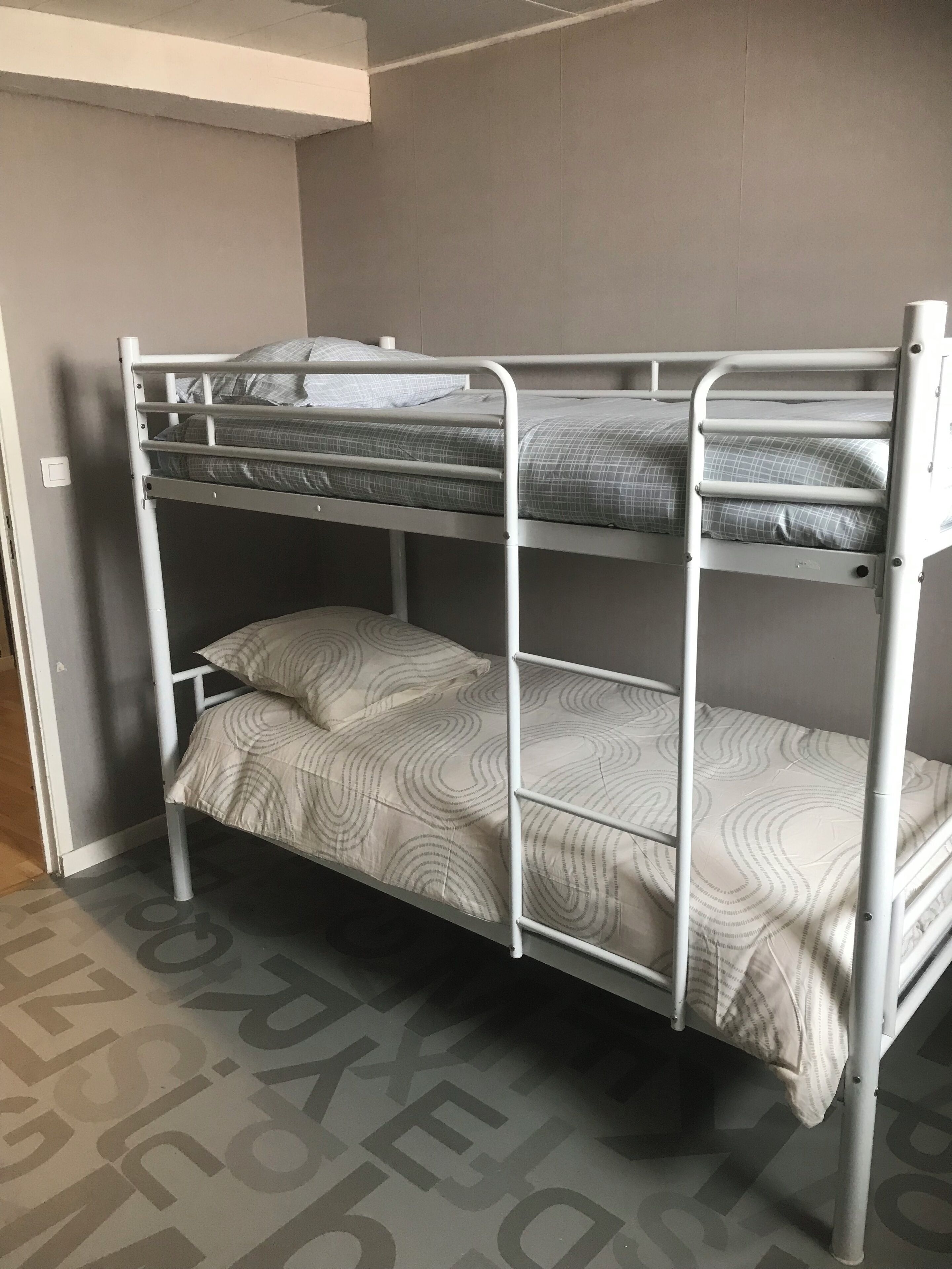 Ein Etagenbett mit drei Schlafstellen, jede mit einer gemusterten Bettdecke.