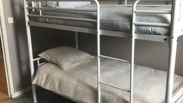 Ein Etagenbett mit drei Schlafstellen, jede mit einer gemusterten Bettdecke.