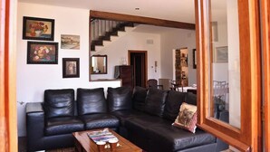 A living room with a black leather sofa, a coffee table with magazines, and a staircase leading to another room. - Villa Ada - detached house, Lake Como view (Argegno)