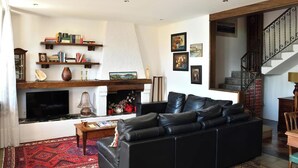 A living room with a fireplace, a black leather sofa, a coffee table, and a bookshelf. - Villa Ada - detached house, Lake Como view (Argegno)
