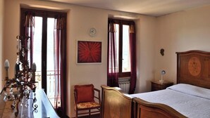 A bedroom with a wooden bed, a chair, a desk with a lamp, and a wall clock. - Villa Ada - detached house, Lake Como view (Argegno)
