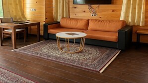 A cozy living room with a sofa, a round coffee table, and a flat-screen TV mounted on the wall. - Bougain Villa Cottage (Bhimtal)