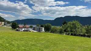 A grassy field with a building and a lake in the background. - Apartment by Lake Ossiach with Mountain Views (Sattendorf)
